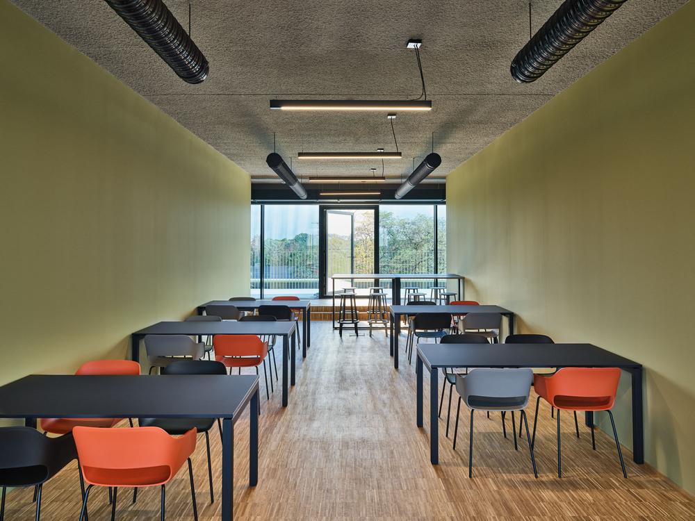 Industrial style meeting room with wooden floor, colorful chairs and ceiling panels